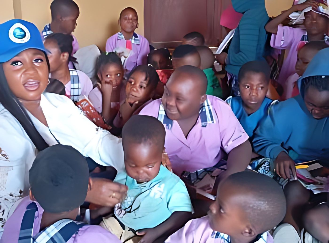 An ISCD volunteer in a blue cap sits among pupils during a Back-to-School outreach